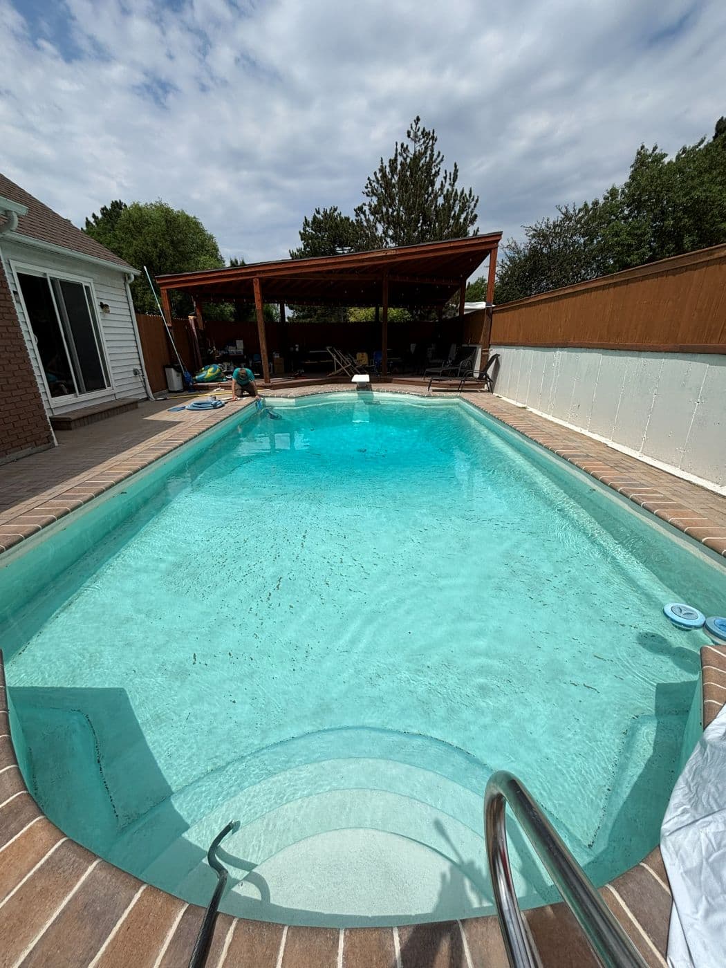 Backyard pool with dirt and debris settled across the floor before service