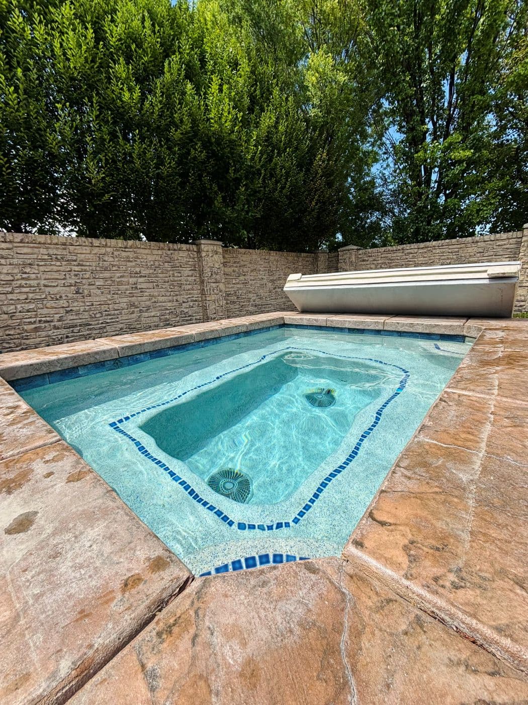 In ground spa with clear water and a stone wall behind