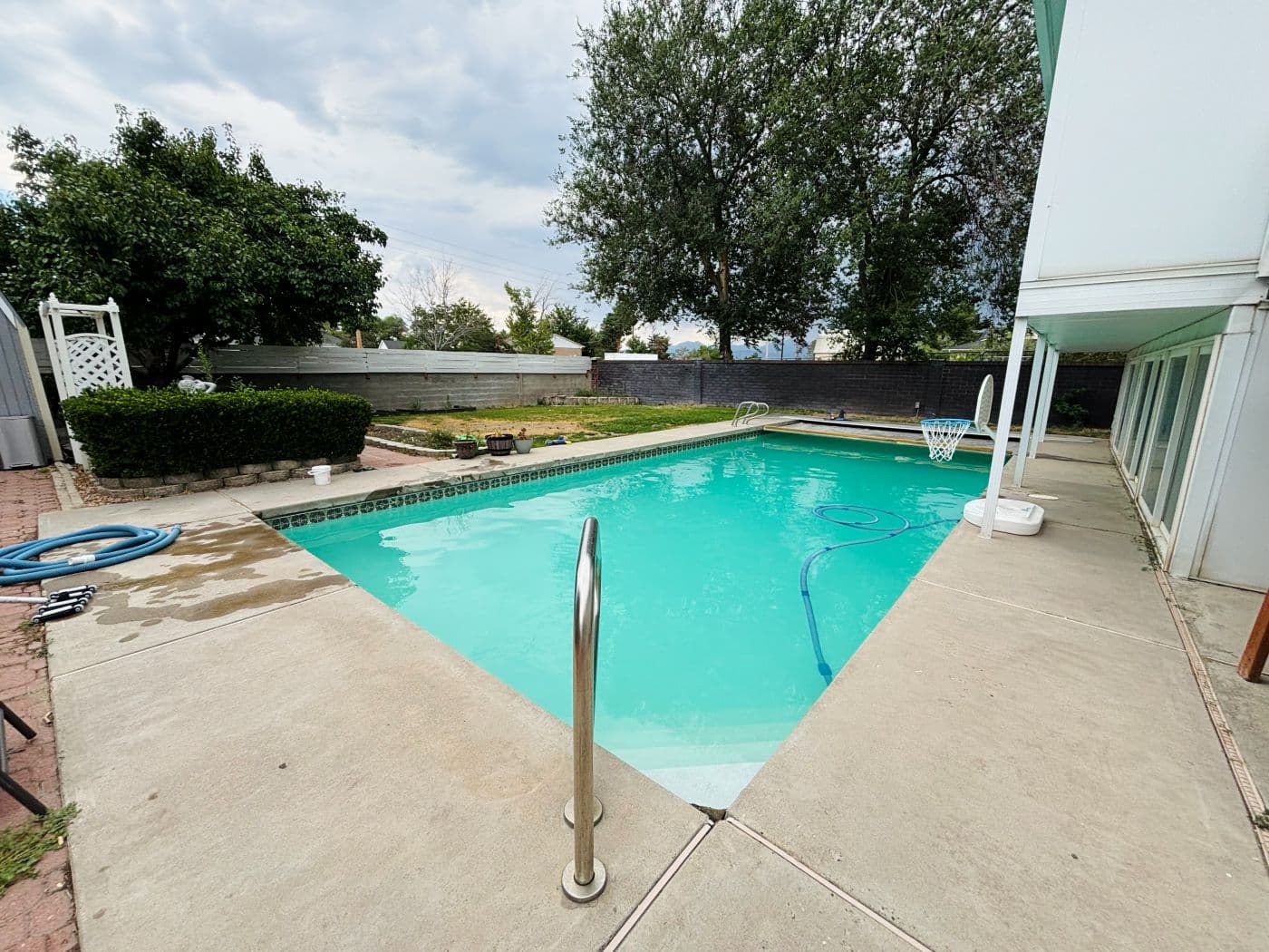 Rectangular pool with teal tinted water under a cloudy sky
