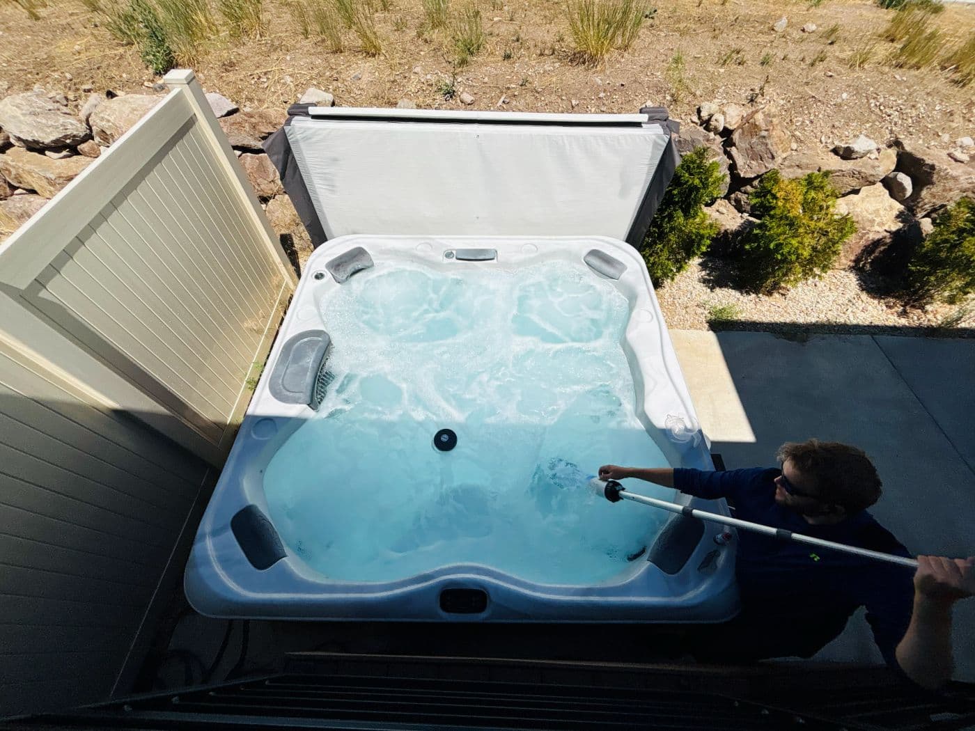 Overhead view of a hot tub being vacuumed with a pole